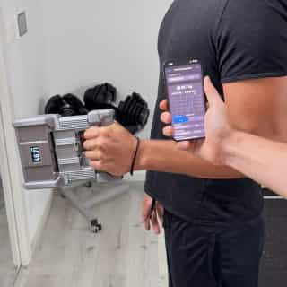 DEXDIA GX being used to measure the grip strength of a person under the supervision of a kinesiologists monitoring their grip strength on the GripMeter app.
